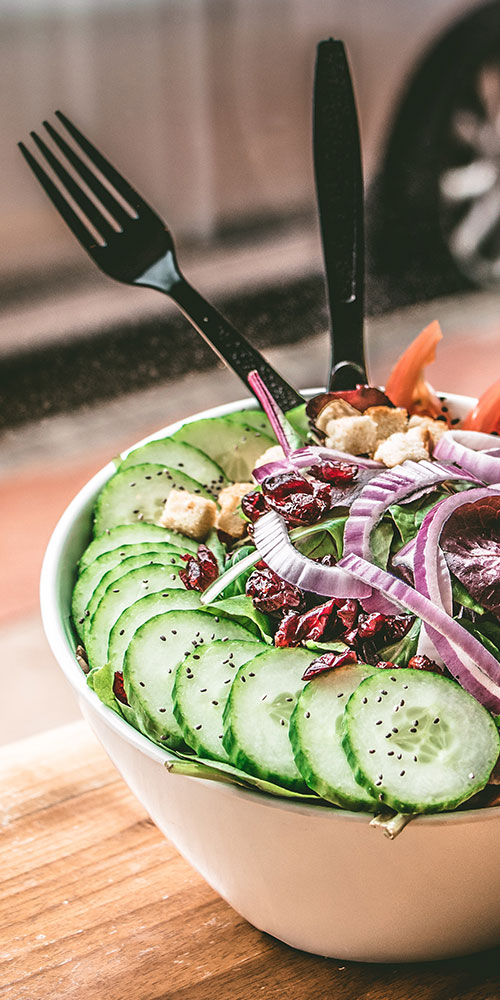 A bowl of salad with cucumbers, onions and olives.