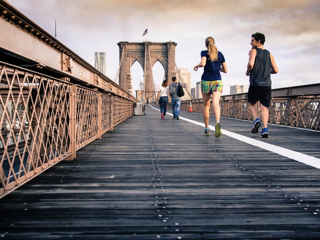 A group of people running across a bridge.