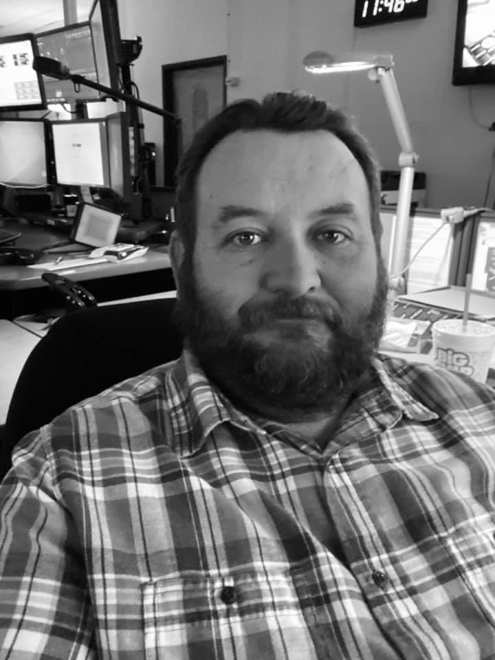 A man with a beard sitting in front of a desk.