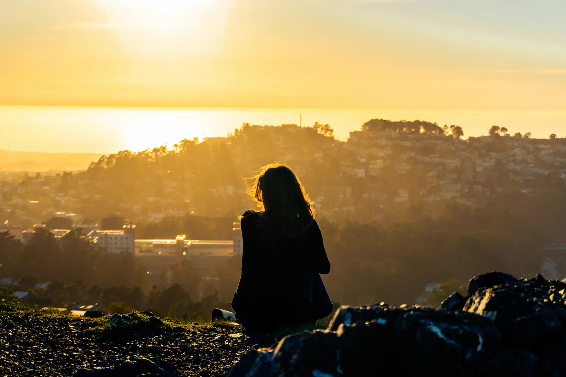 Person sitting on a hillside watching the sunset