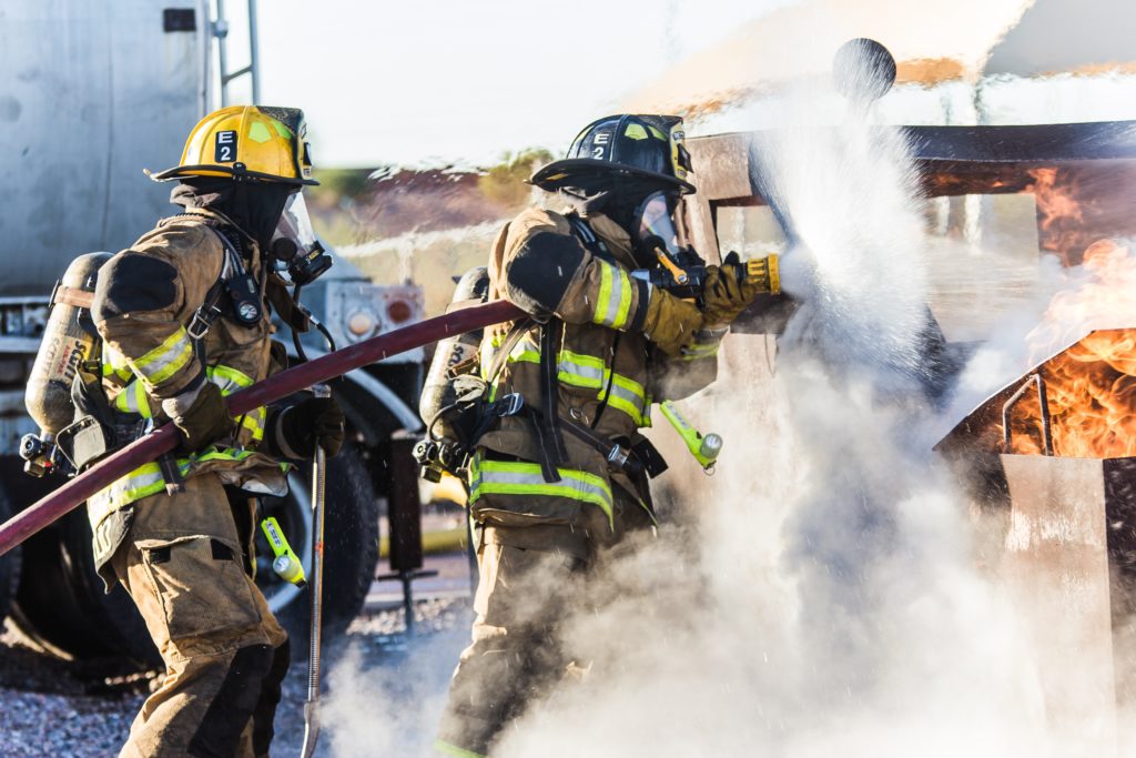 A group of firefighters are spraying water on the fire.